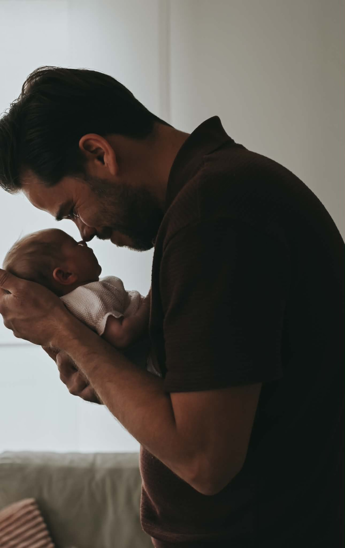 Papa houdt zijn pasgeboren baby teder vast bij het raam