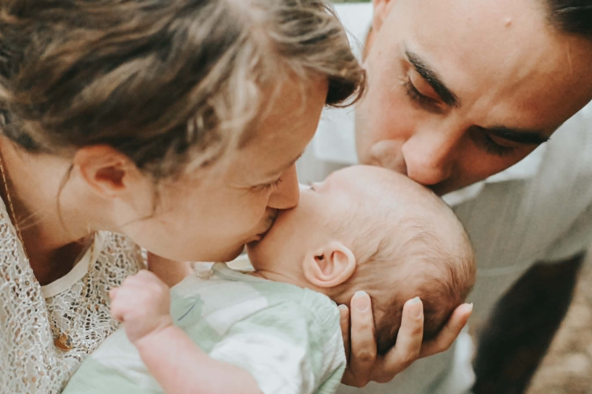 Mama en papa geven hun pasgeboren baby een kus