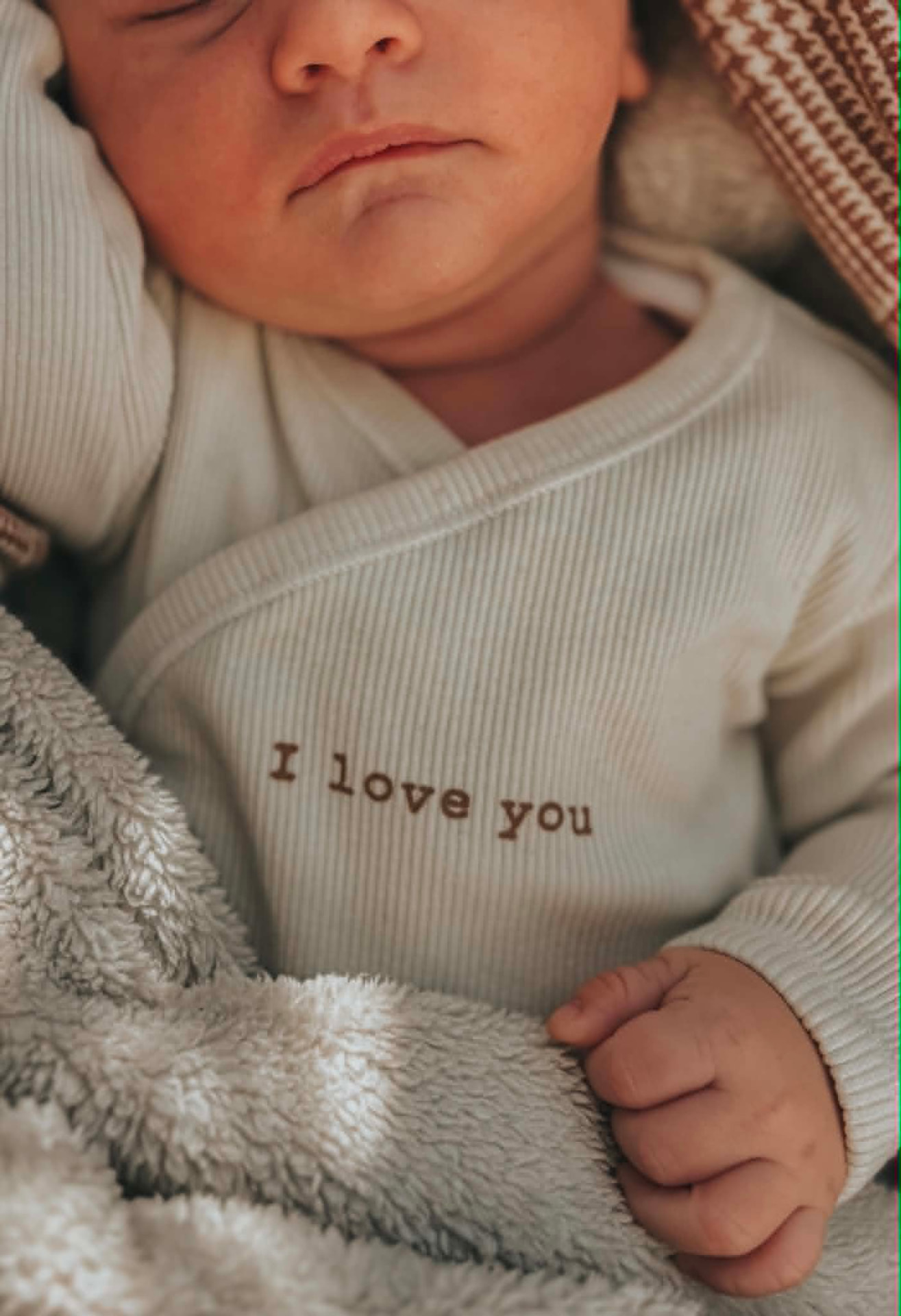 Slapende newborn in een romper met 'I love you'