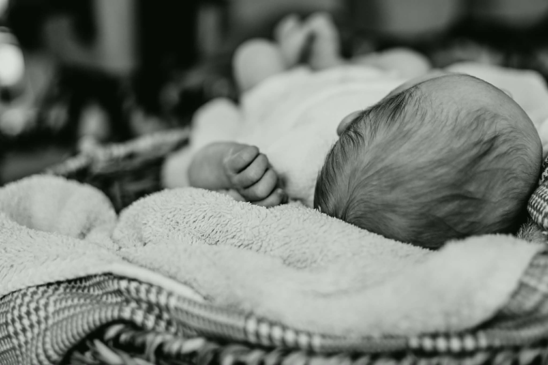 Zwart-witfoto van een slapende newborn in een mandje